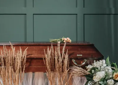 Polished wooden coffin dressed with seasonal flowers, R.C. Smallbone Funeral Directors Newbury
